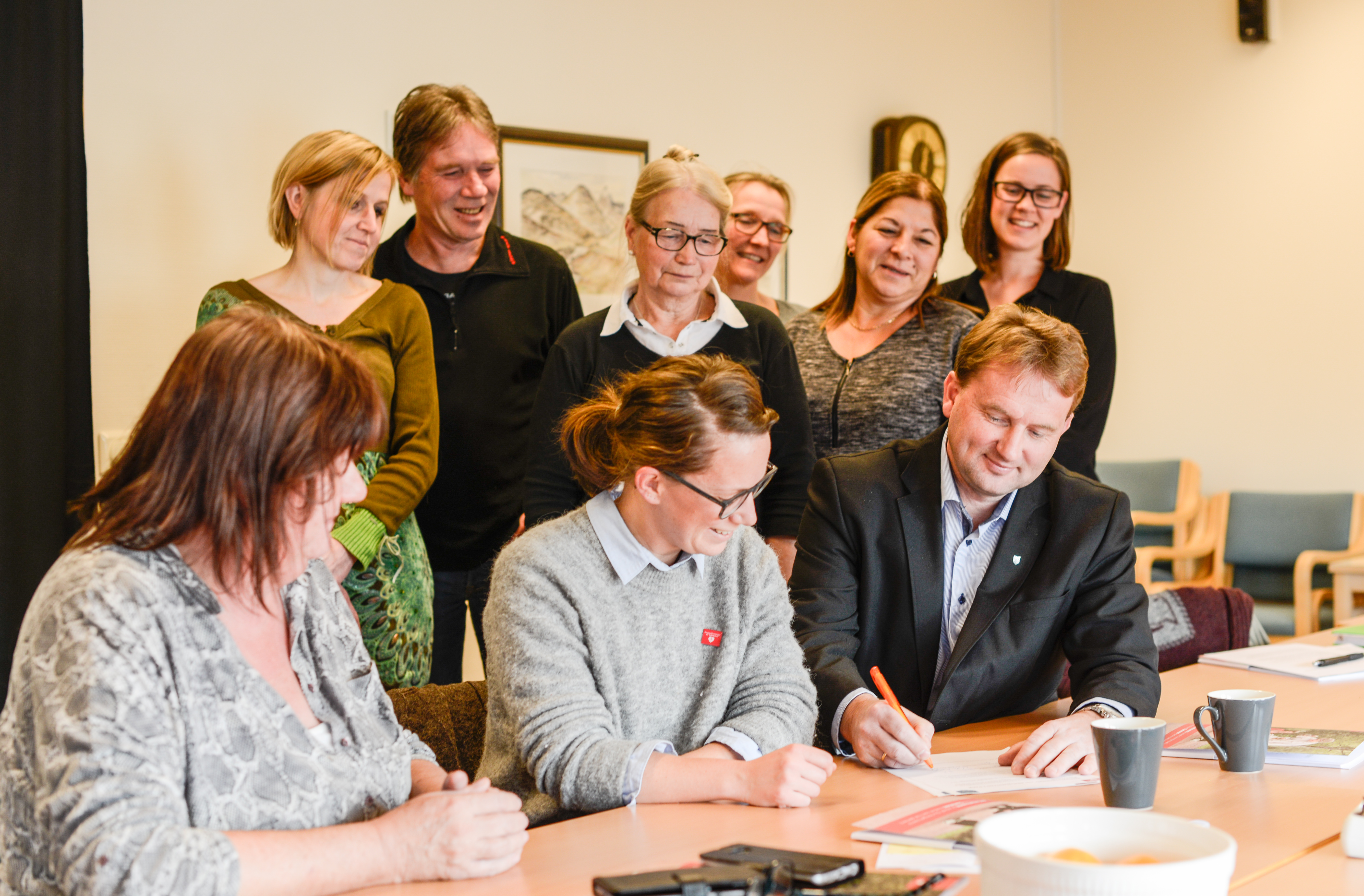 Ordførar Vidar Eltun signerer samarbeidsavtala på vegne av Vang kommune. I midten Josefine Vacker frå Nasjonalforeningen for folkehelse, saman med arbeidsgruppa og Inga Steile  frå eldrerådet (i midten bak).
